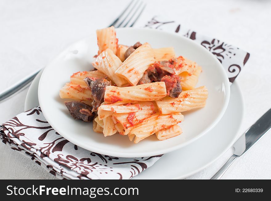 Pasta with meat on a white plate and a thick tomato sauce