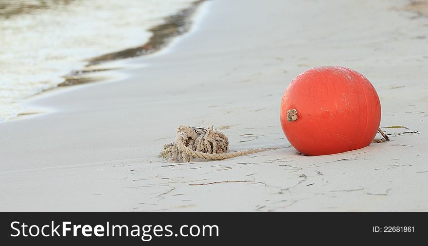 Red ball on the beach with rope waiting for the water to come up