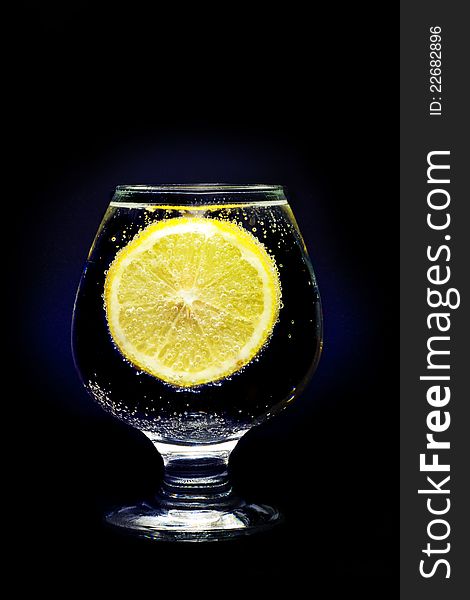 A glass with clear water and lemon isolated on a black background. A glass with clear water and lemon isolated on a black background.