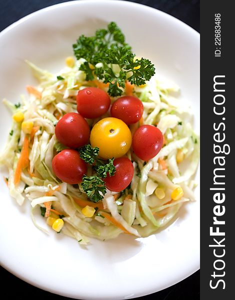 Plate of colourful fresh cabbage salad: corn, carrot, parsley, and cherry tomatoes. Plate of colourful fresh cabbage salad: corn, carrot, parsley, and cherry tomatoes