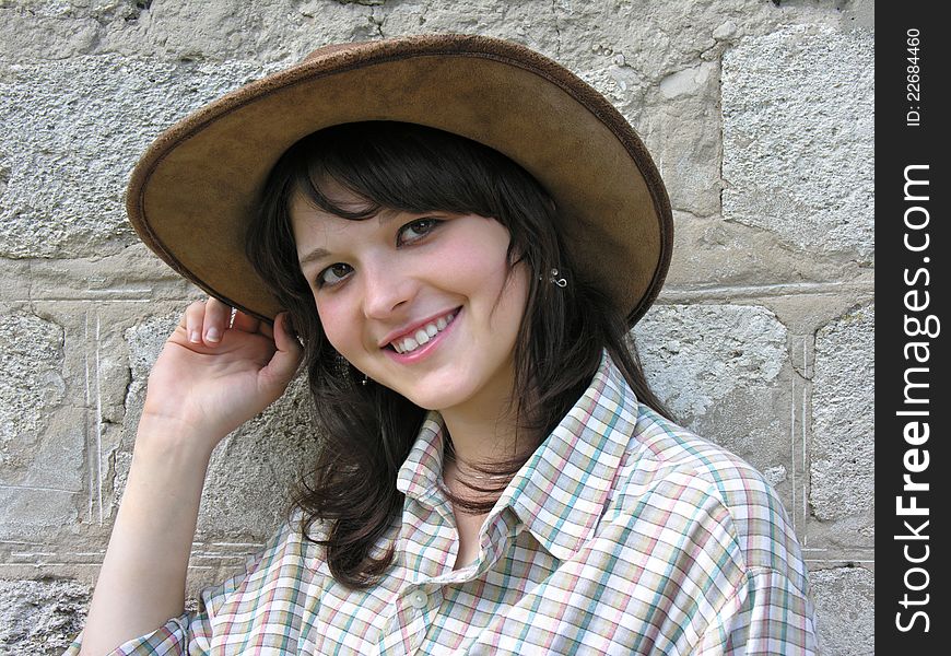 Portrait of young cowgirl near the wall