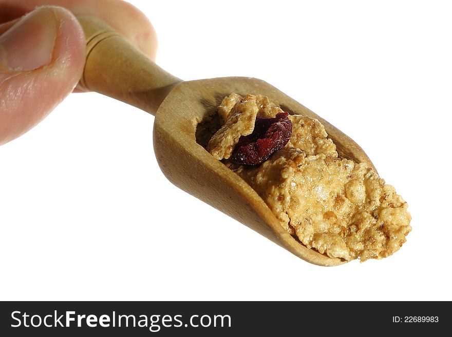 Cereals with dried cherry on wooden spoon, white background.