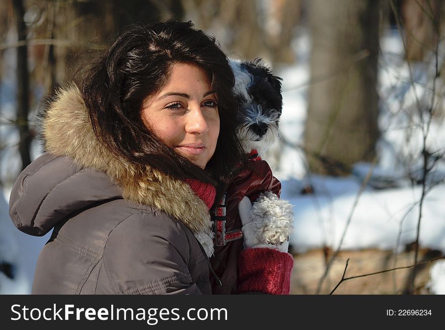 Girl with her small dog in the forest in winter