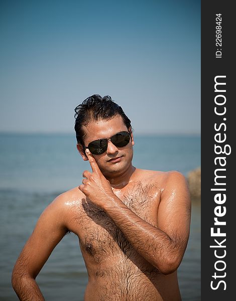 Indian Happy young man getting out of the water with sunglasses. Indian Happy young man getting out of the water with sunglasses