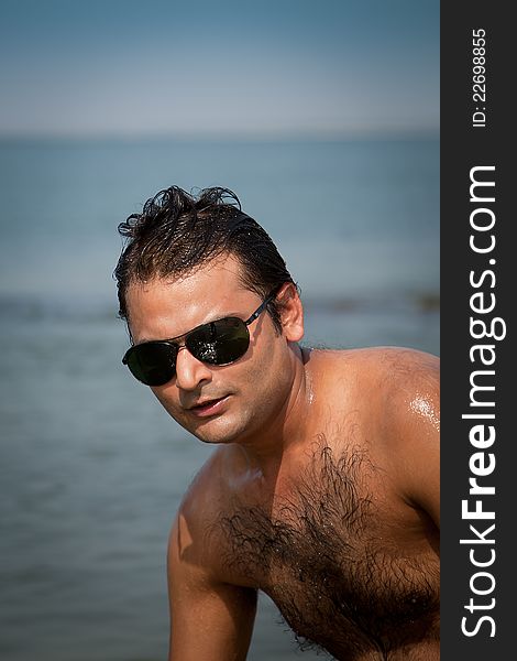 Indian Happy young man getting out of the water with sunglasses. Indian Happy young man getting out of the water with sunglasses