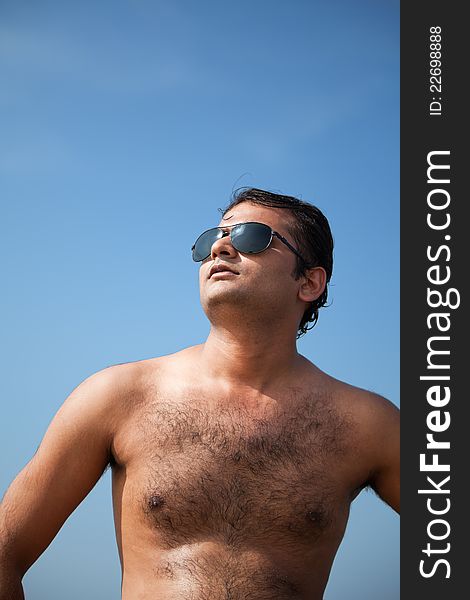 Indian Happy young man getting out of the water with sunglasses under blue sky. Indian Happy young man getting out of the water with sunglasses under blue sky