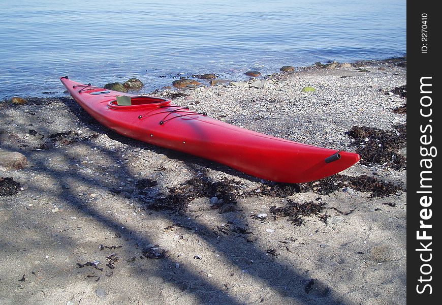 A red canoe on shore by Ol\slo Fjord in Norway