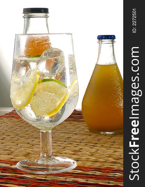 A glass of water with lemon and with bottle on the background. A glass of water with lemon and with bottle on the background