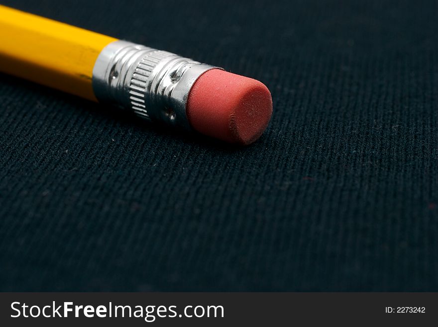 Back of a yellow pencil eraser on a black background