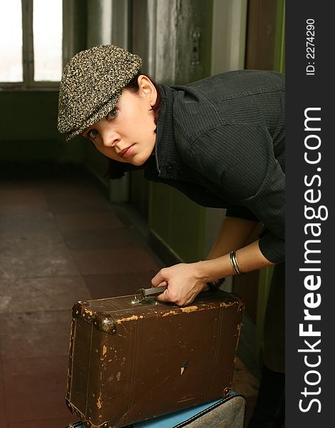 The beautiful woman in a cap with two old suitcases