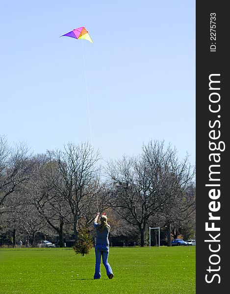 Girl flying a kite in a park with blue sky