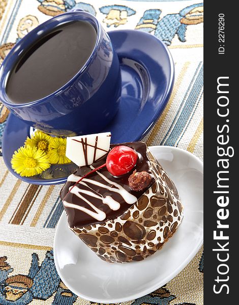 Strong spring fragrant tea in a dark blue cup and cake. Strong spring fragrant tea in a dark blue cup and cake