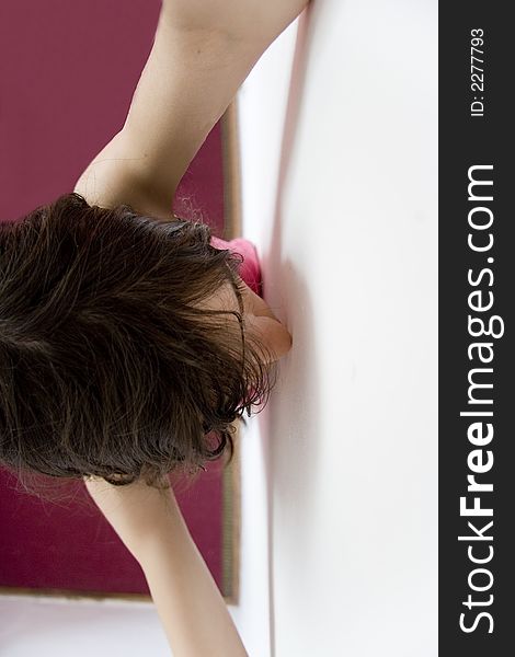 Girl standing near the wall with hands up.