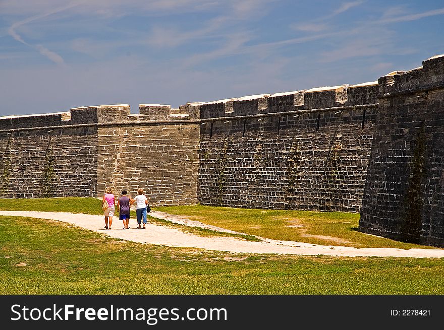 A view of three tourists as they walk along the dry moat that surrounds the old 15th century Spanish fort at St. Augustine, Florida. A view of three tourists as they walk along the dry moat that surrounds the old 15th century Spanish fort at St. Augustine, Florida.