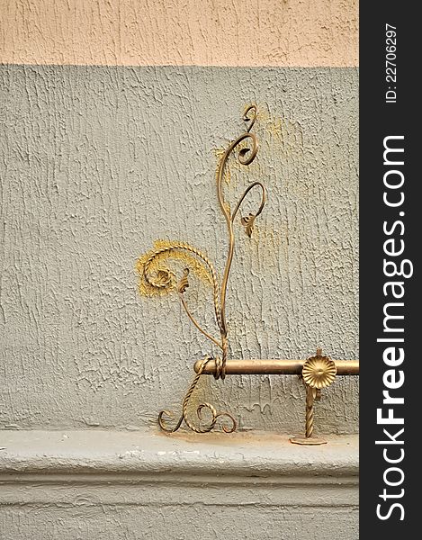 A decorative wrought iron element (handrail) on the exterior wall of a building. A decorative wrought iron element (handrail) on the exterior wall of a building