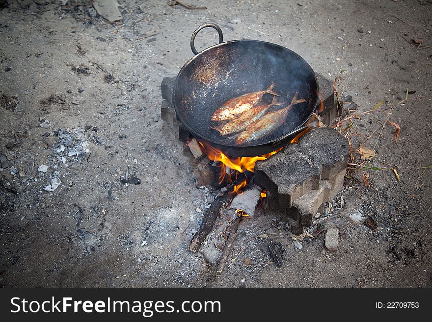 Cooking  three fresh water fish in oil on  open fire. Cooking  three fresh water fish in oil on  open fire