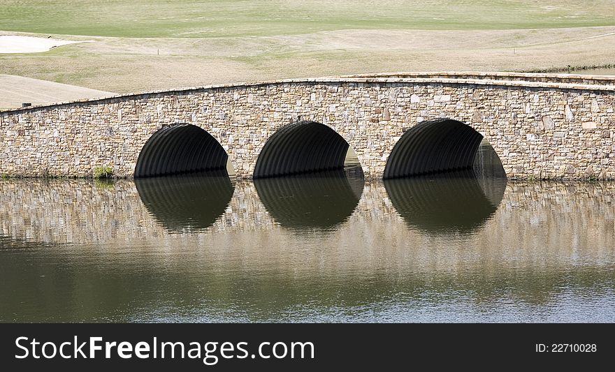 Small stone bridge refects in a pond