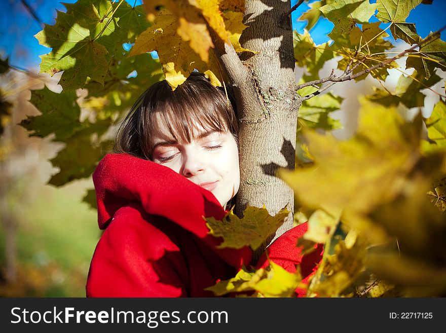 Portrait of a young women in autumn, she is standing under the tree with her eyes closed. Portrait of a young women in autumn, she is standing under the tree with her eyes closed