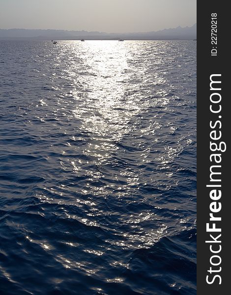 Sea water ripples with horizon and sun track