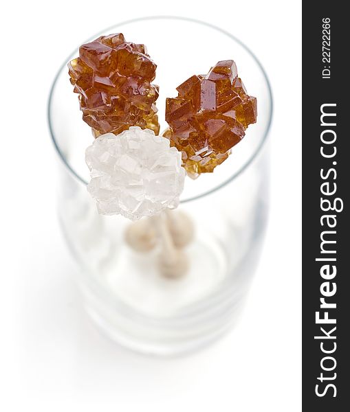 Candy brown and white sugar on a sticks in glass. Soft focus. With white background.