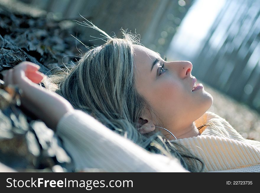 Beautiful blonde girl lying on leaves in a forest of poplars