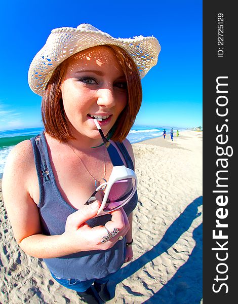 Red Head Girl biting glasses on the beach in HDR