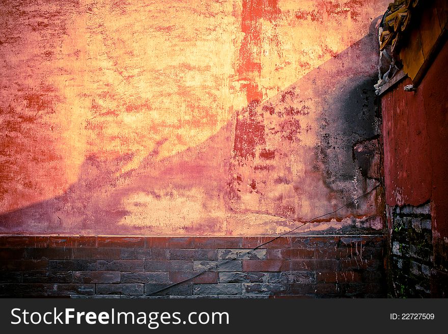 A weathered brick stone wall with red tint