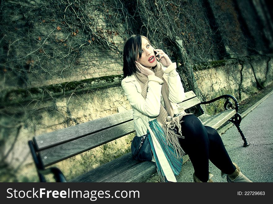 Young woman talking on phone on the bench