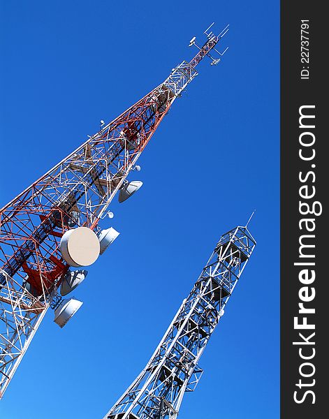 Two telecommunication towers on blue sky, antennas