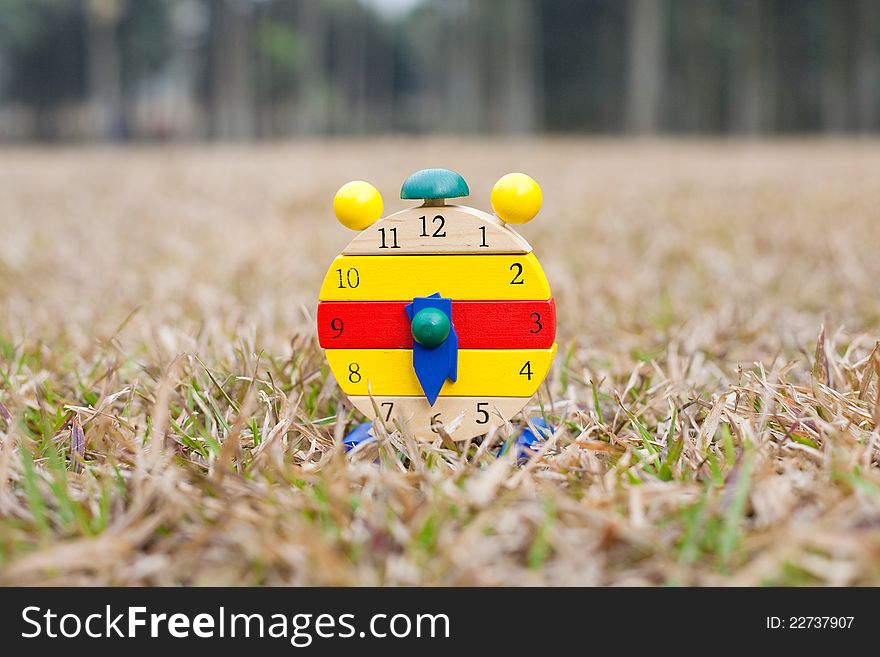 Wood clock on grass at  autumn afternoon