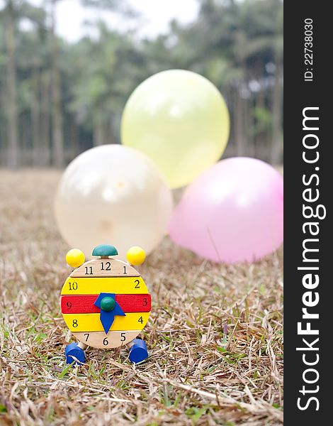 Wood clock on grass with colorful balloons. Wood clock on grass with colorful balloons