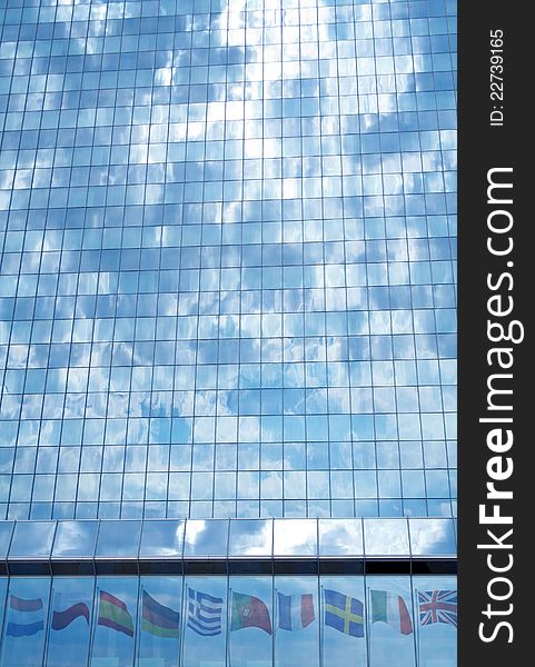 Storm clouds over the European Union concept - glass building facade reflecting flags and sky