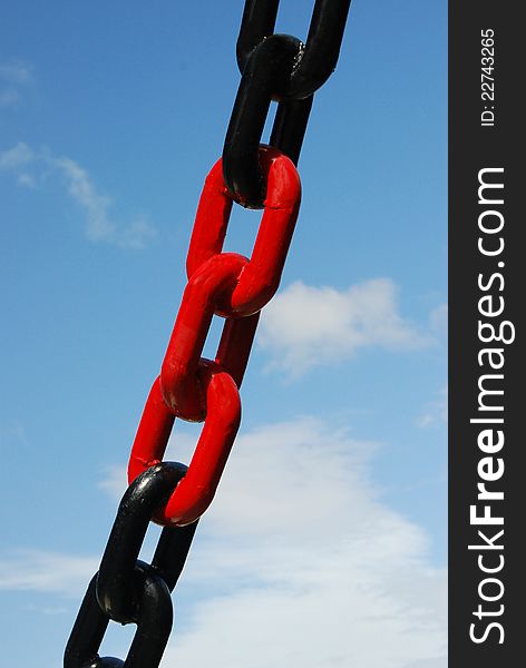 Red and black colored chain with blue sky on background