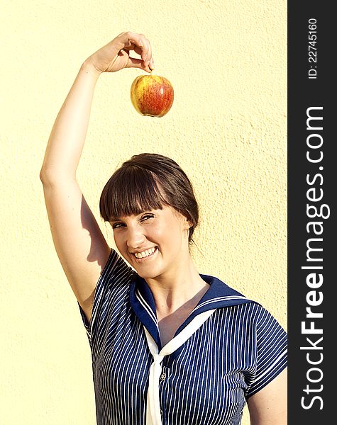 Beautiful happy girl on the background of the wall with an apple. Beautiful happy girl on the background of the wall with an apple