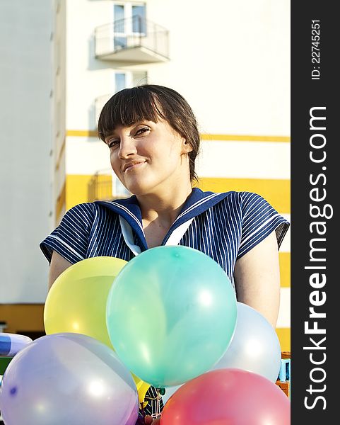 A beautiful girl on the swing is holding balloons. A beautiful girl on the swing is holding balloons