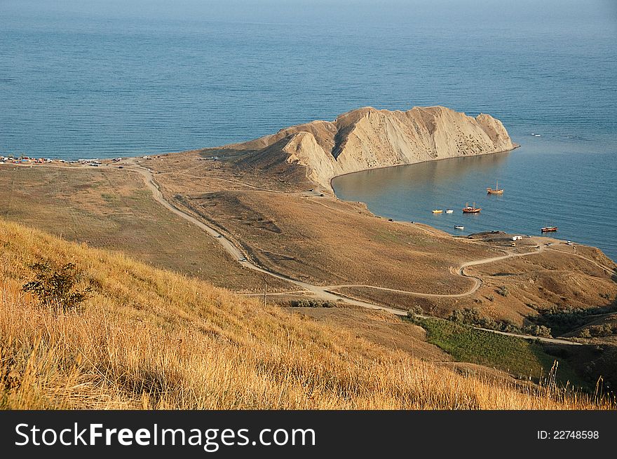 View from hill at coastline with mountains in distance. View from hill at coastline with mountains in distance