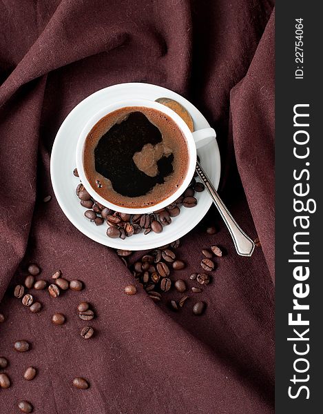 Hot coffee and coffee beans on a brown linen