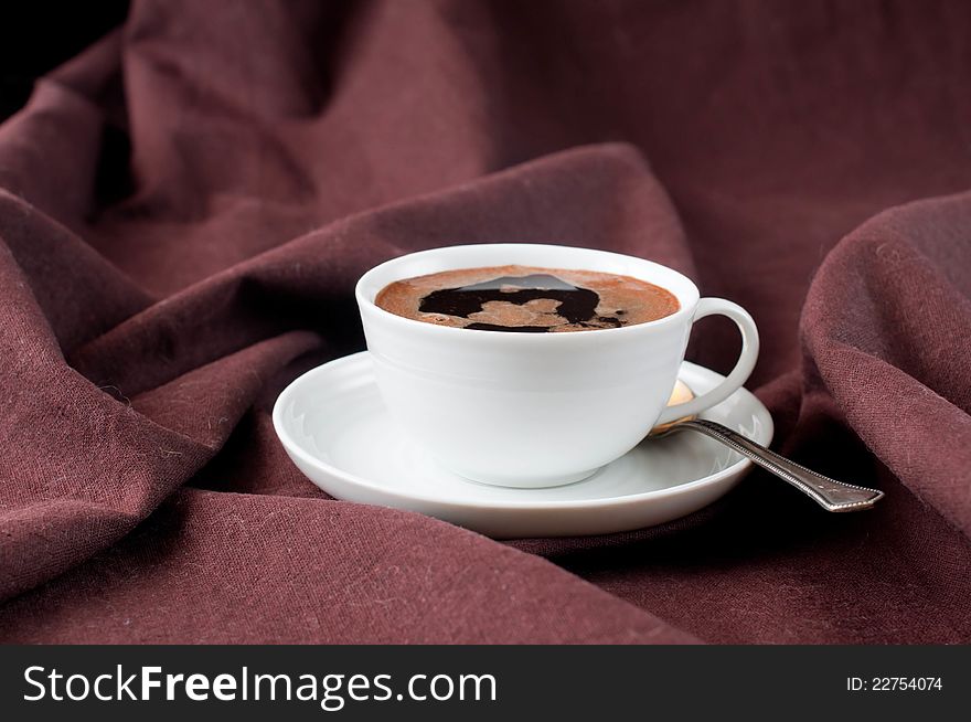 A cup of hot coffee in a brown linen