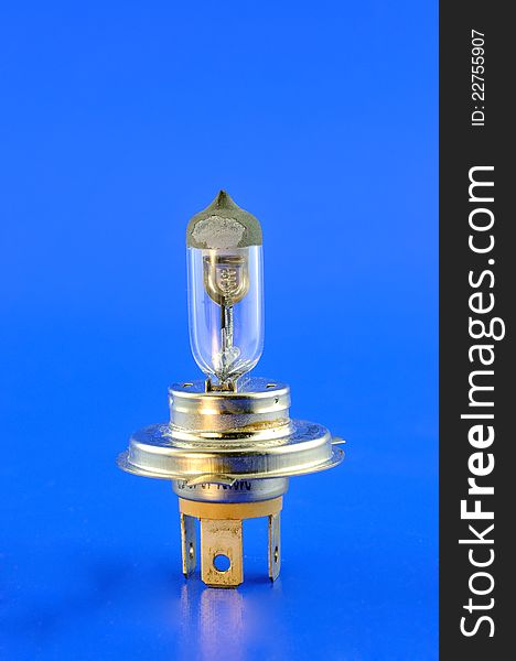 Car halogen bulb stands in the foreground against a blue background. Car halogen bulb stands in the foreground against a blue background