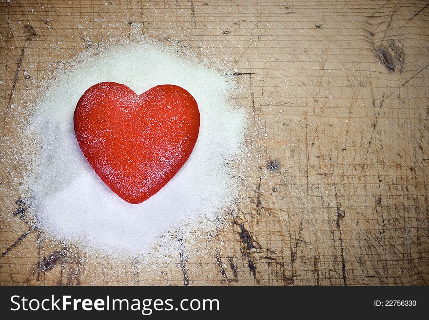 Read heart sitting on sugar on wood background. Read heart sitting on sugar on wood background