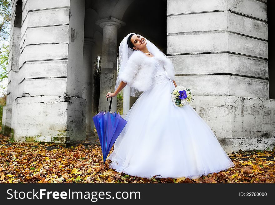 Beautiful bride with umbrella in autumn park