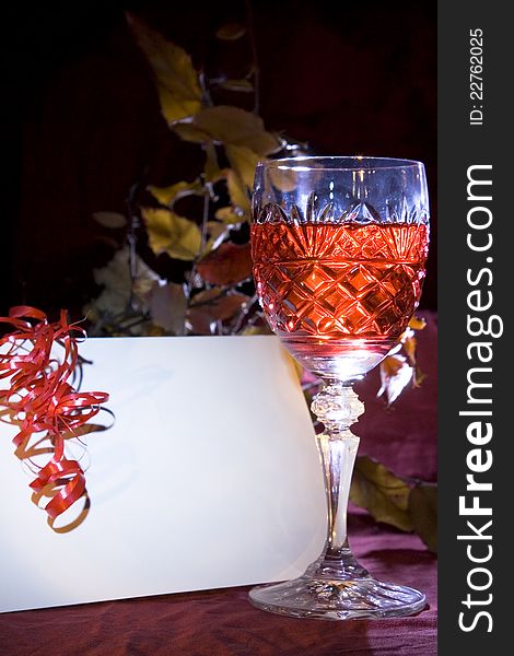 Crystal wine glass with autumn background with white board card for your text. Crystal wine glass with autumn background with white board card for your text