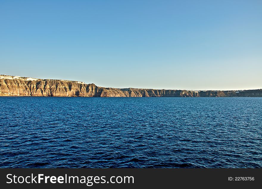 A high stone wall overlooking the sea. This stone stands in front of the island of Santorini travelers. Its shores are steep and precipitous. A high stone wall overlooking the sea. This stone stands in front of the island of Santorini travelers. Its shores are steep and precipitous.