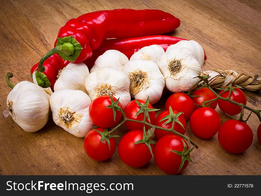 Peppers, cherry tomatoes and garlic on the wooden background. Peppers, cherry tomatoes and garlic on the wooden background
