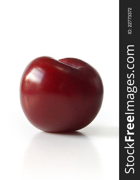 Macro studio shot of a red plum  on white background with slight reflection and soft shadows. Copy space. Macro studio shot of a red plum  on white background with slight reflection and soft shadows. Copy space.