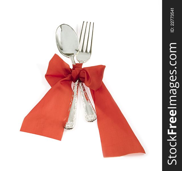 Spoon and fork are bandaged by a red ribbon. Spoon and fork are bandaged by a red ribbon