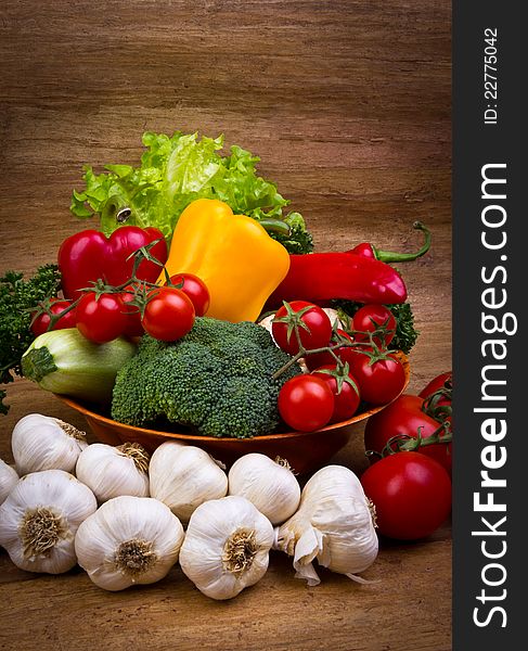 Fresh vegetables in the bowl on the wooden background