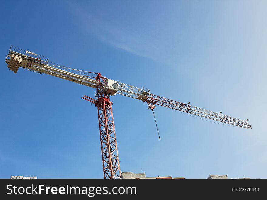 Construction crane at the construction site, on a cloudless sky