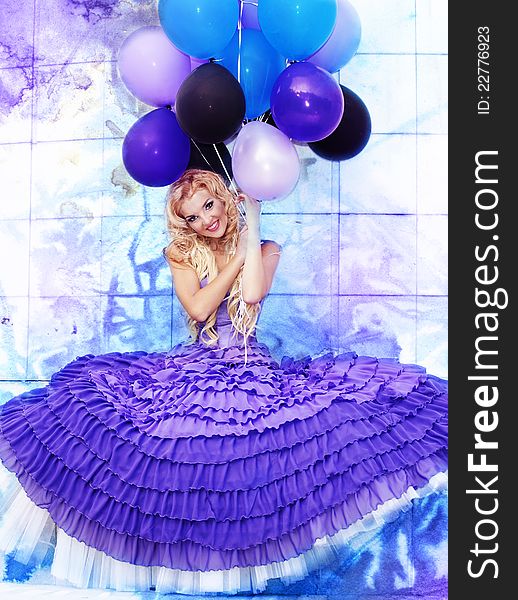 Beautiful girl in the purple dress with balloons in the background sky