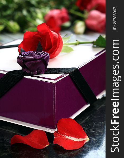 Image of a rose with a box of chocolates sitting on a table in daylight. Image of a rose with a box of chocolates sitting on a table in daylight